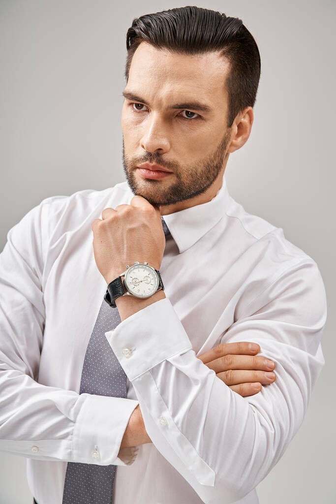 Porträt eines seriösen Geschäftsmannes im Anzug, der selbstbewusst vor grauem Hintergrund posiert - Foto, Bild