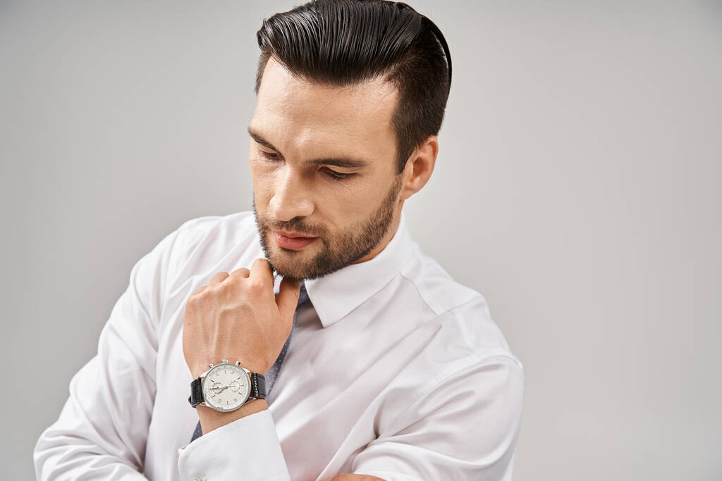 πορτραίτο σοβαρού επιχειρηματία με λευκό πουκάμισο και γραβάτα που ποζάρει με αυτοπεποίθηση σε γκρι φόντο - Φωτογραφία, εικόνα