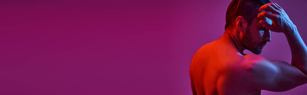 retrato de hombre musculoso y sin camisa posando sobre fondo púrpura con luces rojas y azules, estandarte - Foto, Imagen