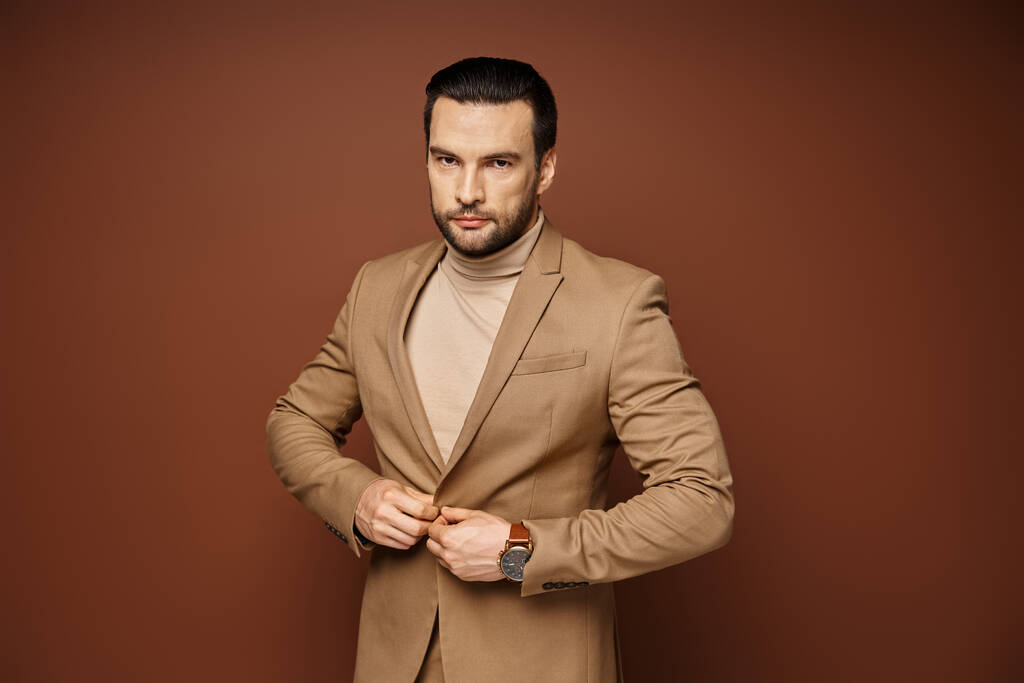 portrait d'homme confiant et beau avec soies en tenue élégante posant sur fond beige - Photo, image