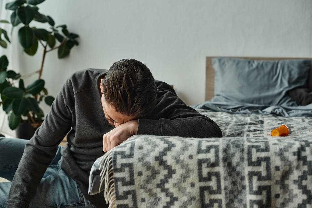 bebaarde man die lijdt aan pijn en leunend op een grijze deken op bed in de moderne slaapkamer, pijn - Foto, afbeelding