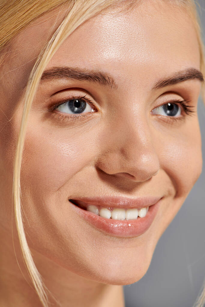 close-up shot van mooi meisje met brede glimlach en gezonde tanden in grijze achtergrond - Foto, afbeelding