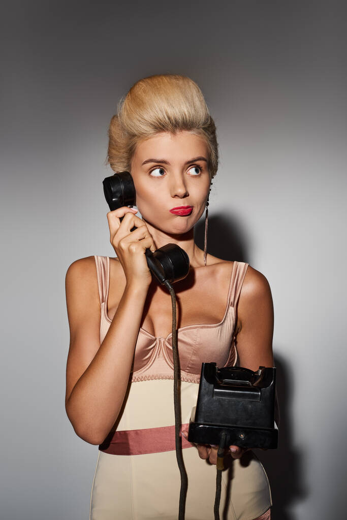 bájos fiatal nő piros rúzs zavaros beszélgetés retro telefon szürke háttér - Fotó, kép