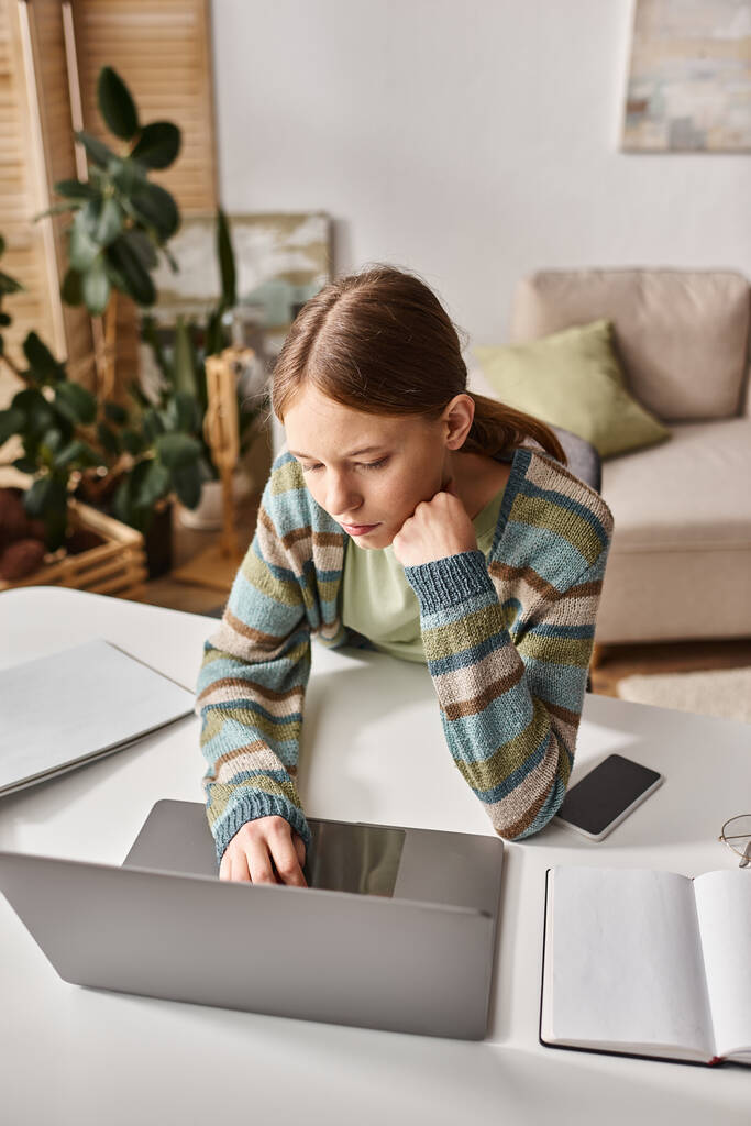 dospívající dívka se soustředí na e-learning s notebookem a smartphonem na svém stole doma, domácí úkoly - Fotografie, Obrázek