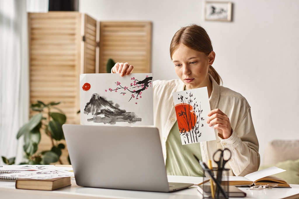 Девочка-подросток, показывающая свои работы во время учебы и глядя на свой ноутбук, онлайн-класс искусств - Фото, изображение