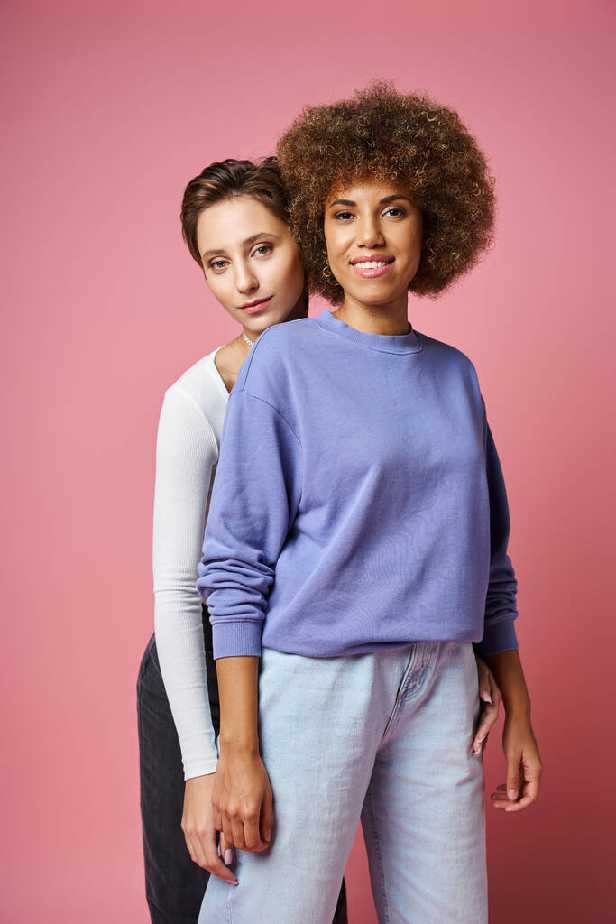 feliz joven multicultural lgbt pareja en ropa casual posando juntos sobre fondo rosa - Foto, imagen