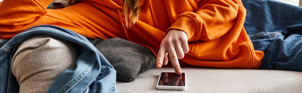10代の女の子がスマートフォンをブラウズし,ソファーで休んでいる間にダウンを感じるバナー - 写真・画像