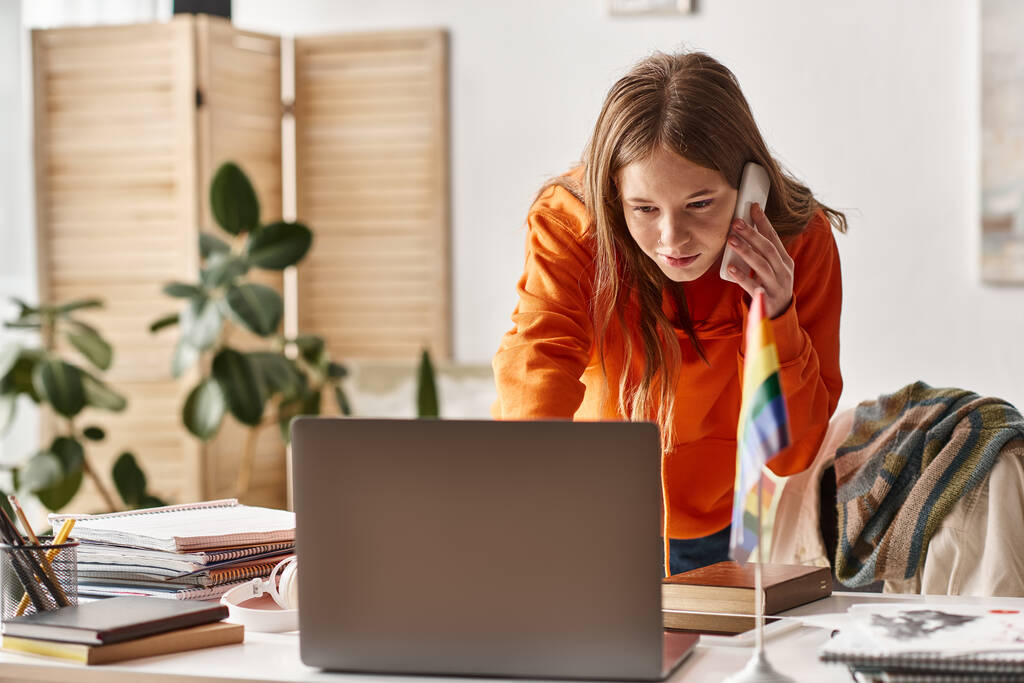 soustředěný teenager dívka studuje on-line z domova, dělat hovor vedle pýchy Igbtq vlajka na stole - Fotografie, Obrázek