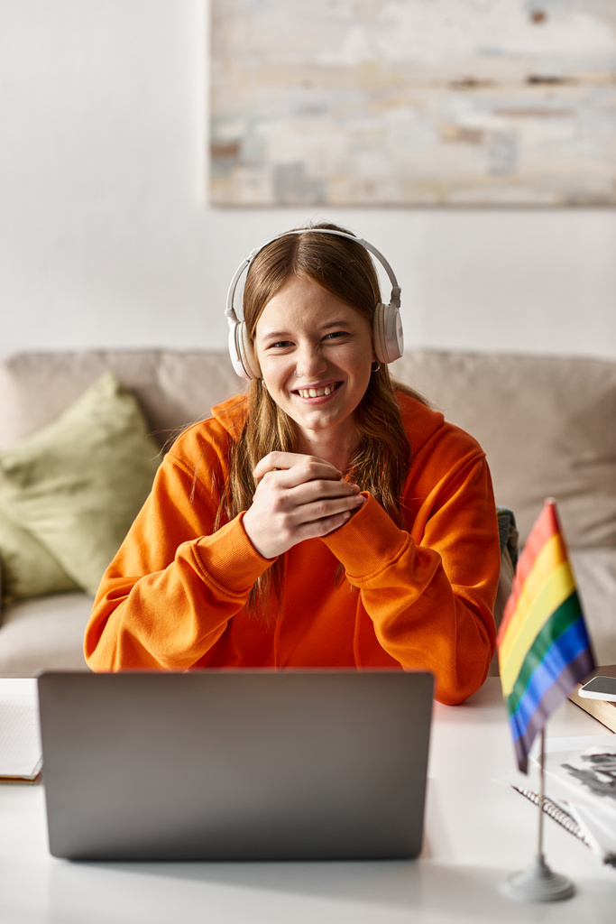 Kulaklıklı mutlu genç kız dizüstü bilgisayar ve gurur bayrağı ve dayanışmanın yanında müzik dinliyor. - Fotoğraf, Görsel