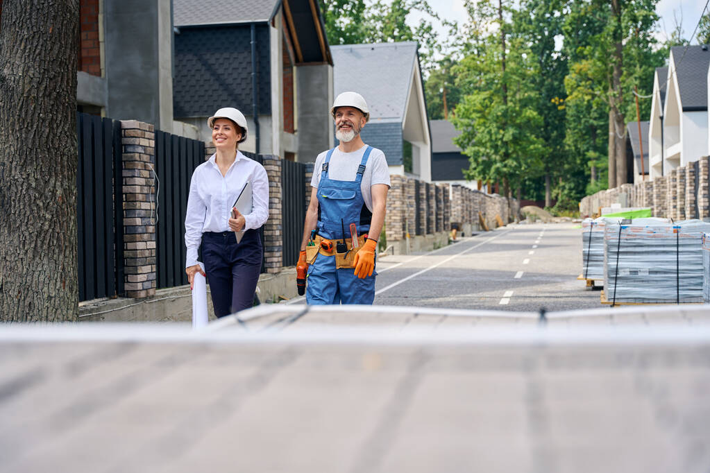 Inspecteur de bâtiment joyeux et constructeur debout sur la rue devant la maison inachevée - Photo, image