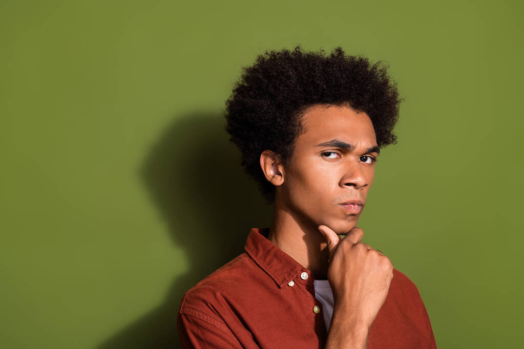 Zdjęcie portret atrakcyjny młody mężczyzna dotyk podbródek wygląd poważne umysły nosić modne brązowe ubrania odizolowane na tle koloru khaki. - Zdjęcie, obraz