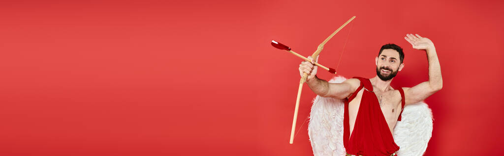 赤,バレンタインデー,水平バナーにハート型の矢でアーチャーする笑顔のカイドマン - 写真・画像