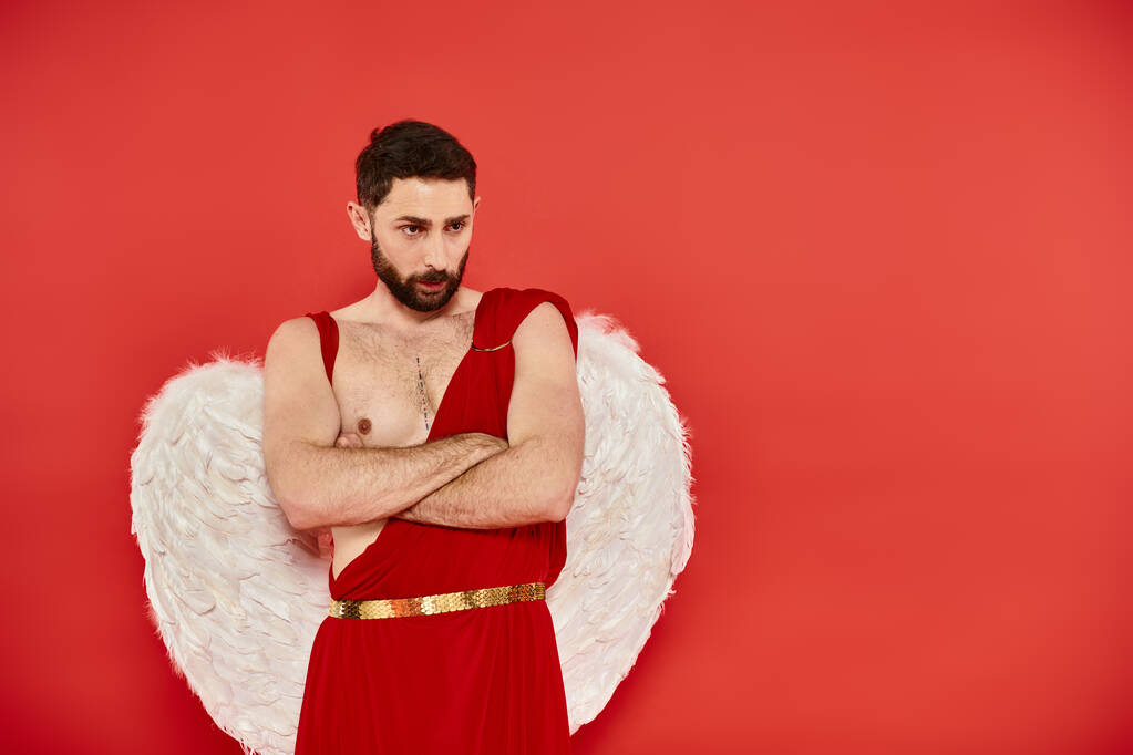 homme Cupidon sérieux et réfléchi avec les bras croisés debout sur fond rouge, Saint Valentins concept - Photo, image