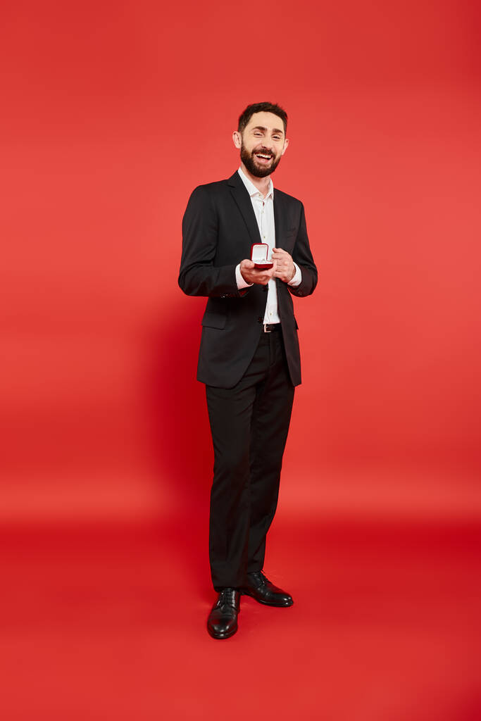полная длина успешного возбужденного бизнесмена с шкатулкой ювелирных изделий смеясь на красный, st валентинки - Фото, изображение