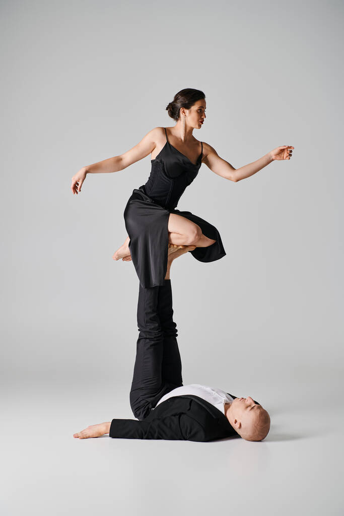 Dynaaminen duo, pari akrobaattia esittämässä tasapainoesitystä studiossa, jossa on harmaa tausta - Valokuva, kuva