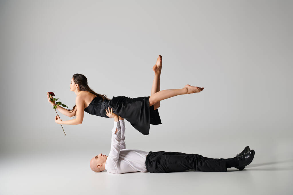 танцівниця лежить на підлозі і піднімає тіло жінки з червоною трояндою під час танцювального виступу - Фото, зображення