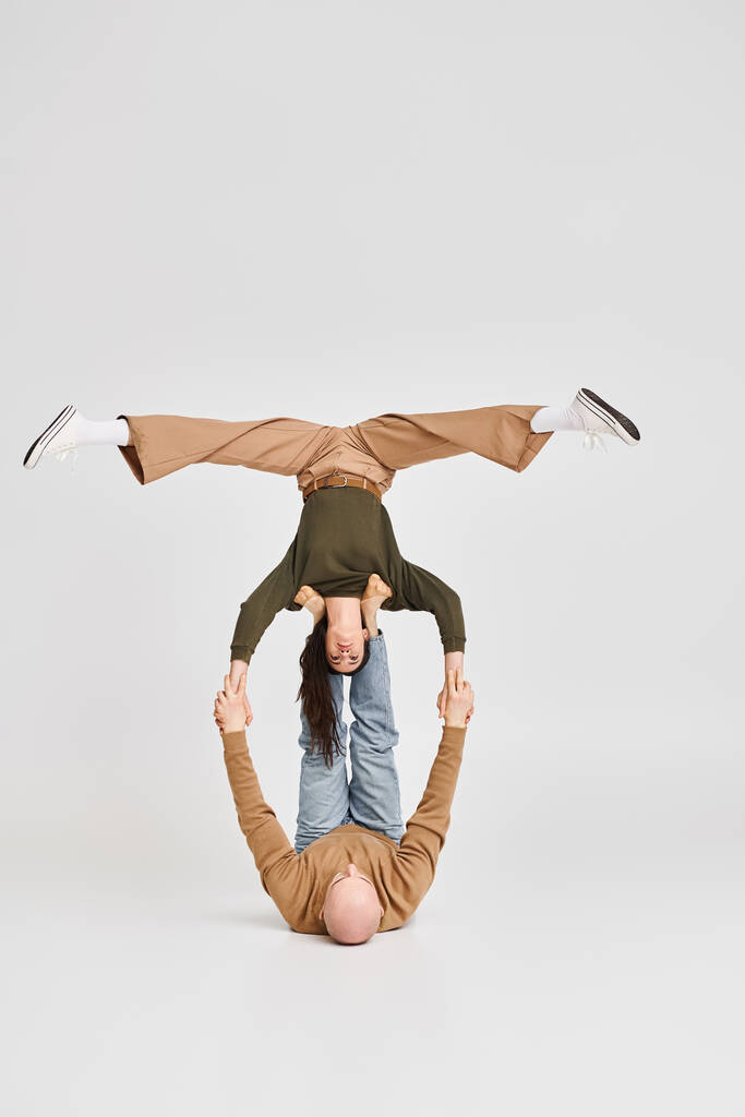 Künstlerisches Paar, akrobatische Frau balanciert kopfüber mit Unterstützung des Mannes im Atelier - Foto, Bild