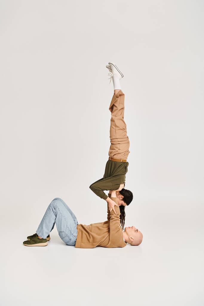 brunette naaras akrobaatti rento kulumista tasapainotus käsissä vahva mies, pari harjoitellaan studiossa - Valokuva, kuva