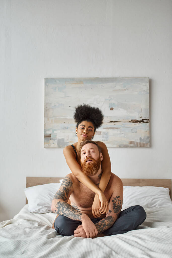 Mutlu çift, seksi Afrikalı Amerikalı kadın evde dövmeli erkek arkadaşını kucaklıyor. - Fotoğraf, Görsel