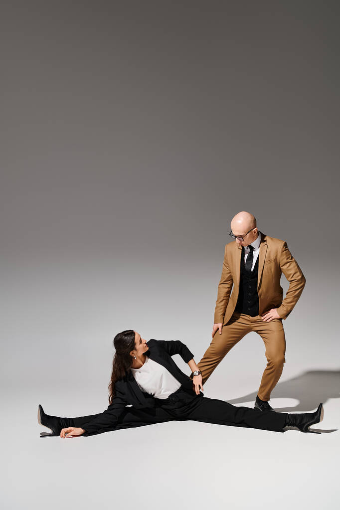 női akrobata elegáns vállalati öltönyben, osztott és kézen fogva férfi a stúdióban - Fotó, kép
