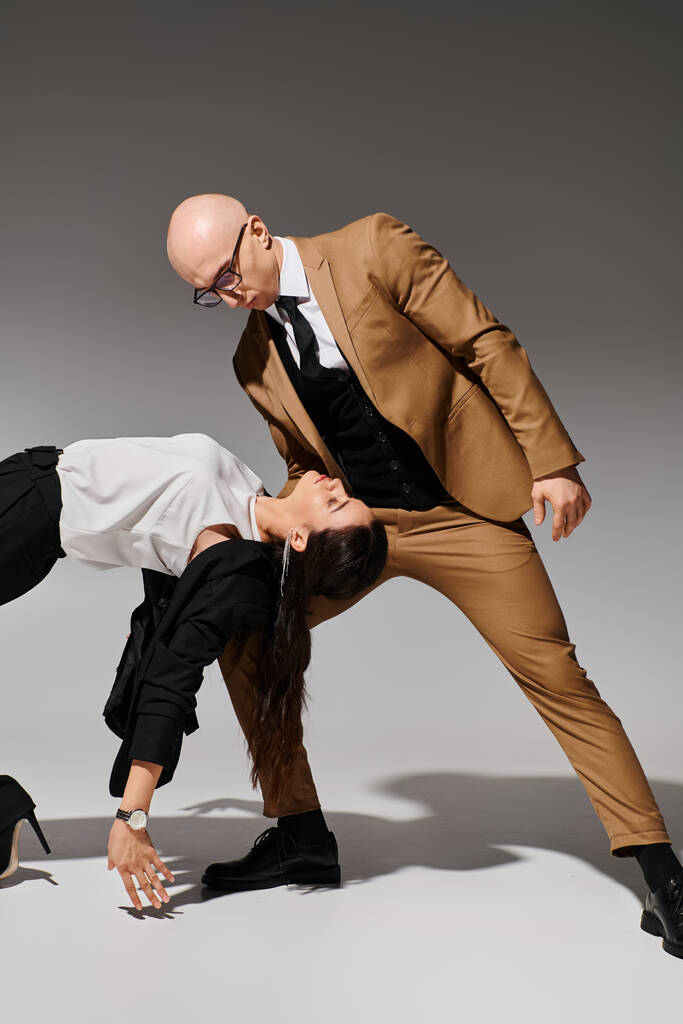 Geschäftspartner in einem koordinierten Tanzschritt, gemeinsam im Studio vor grauem Hintergrund - Foto, Bild