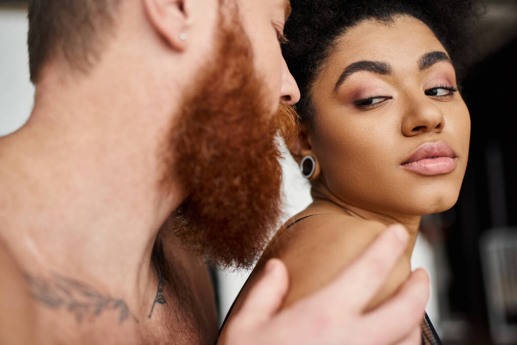 bearded man with tattoos seducing sensual african american woman in lingerie, diverse couple - Photo, Image