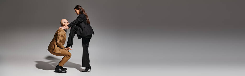 brunette vrouw balanceren in hoge hakken terwijl stappen op de hand van danspartner in pak, banner - Foto, afbeelding