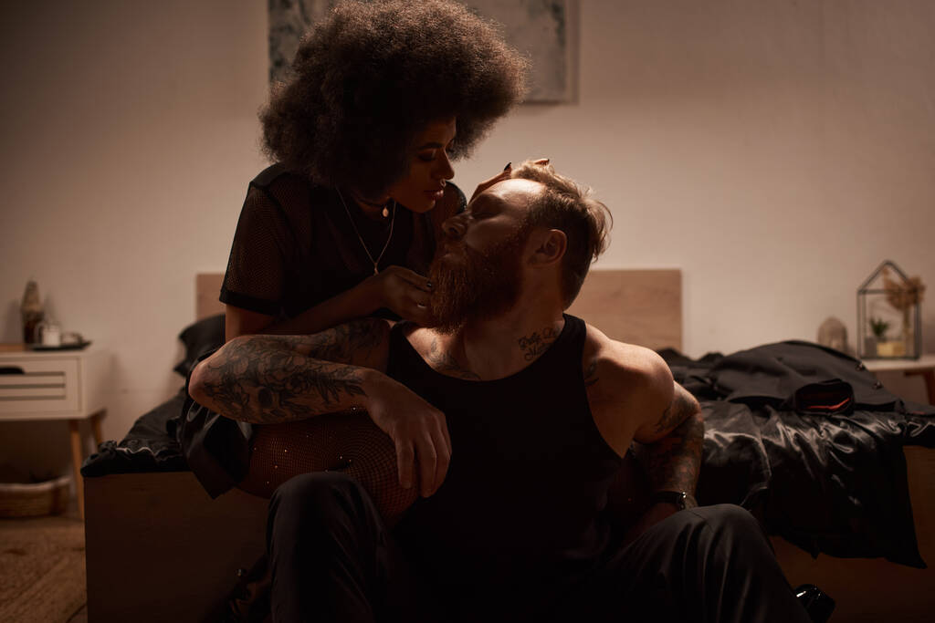 férfi tetoválásokkal ül közelében csábító afro-amerikai nő necces harisnyanadrágban strasszos - Fotó, kép