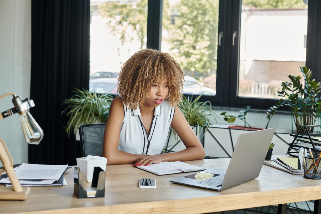 афроамериканська бізнес-леді дивиться на ноутбук під час відеодзвінка в сучасному офісі, робочий день - Фото, зображення
