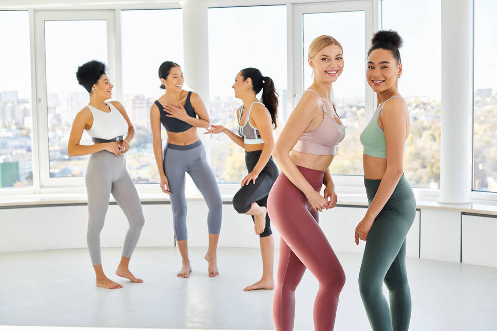 group of cheerful multicultural women in sportwear chatting before pilates class, look at camera - Photo, Image