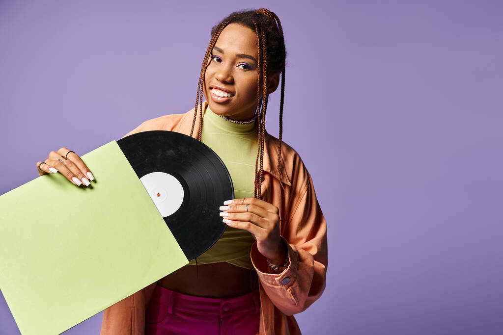 幸せな若いアフリカ系アメリカ人女性 20代のドレッドロックは紫色の背景にビニールのディスクを保持 - 写真・画像