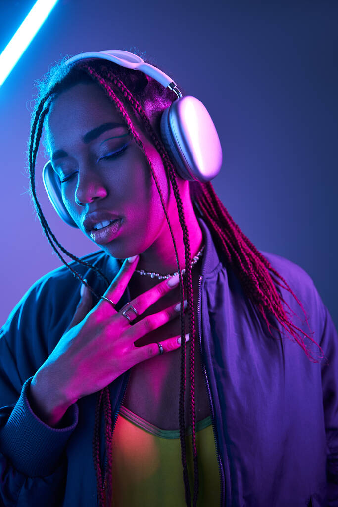 蛍光灯でスタジオで音楽を楽しんでいるヘッドフォンのアフリカ系アメリカ人女性 - 写真・画像