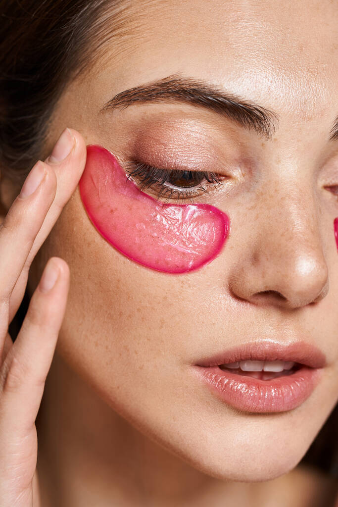 Uma jovem mulher caucasiana com pele limpa e remendo de olhos rosa em seu rosto em um ambiente de estúdio. - Foto, Imagem