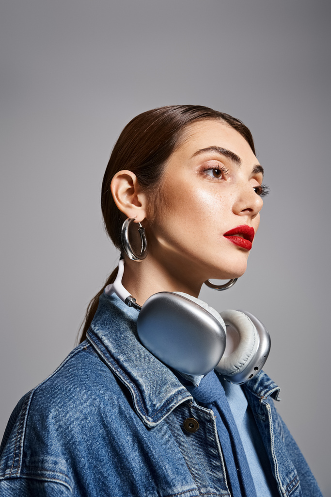 Uma jovem mulher caucasiana elegante em uma jaqueta de ganga ouvindo música através de fones de ouvido. - Foto, Imagem