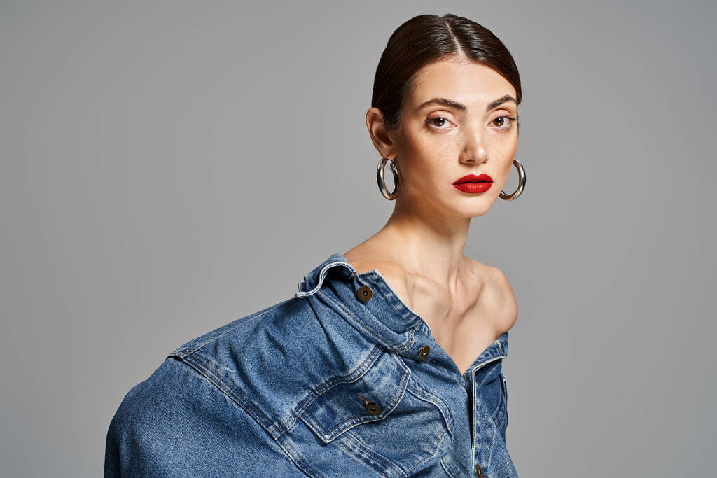 A young Caucasian woman with brunette hair and clean skin rocks a denim shirt paired with bold red lipstick. - Photo, Image
