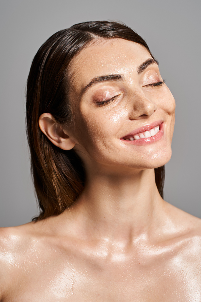 A young Caucasian woman with brunette hair and closed eyes smiling in studio - Photo, Image