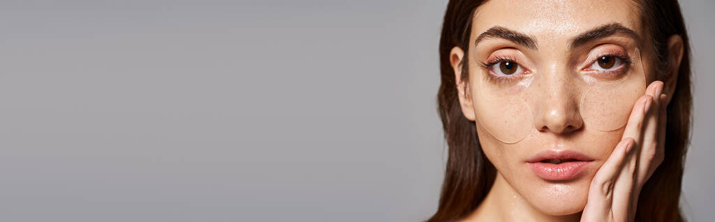 Eine junge Frau mit brünetten Haaren zeigt eine atemberaubende Schönheit in Augenklappen, blickt in Kamera, Banner - Foto, Bild
