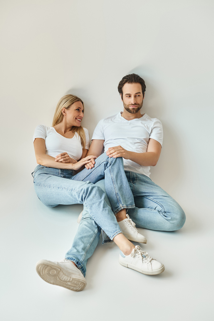 Um casal romântico, o homem e a mulher, sentam-se juntos no chão, compartilhando um momento íntimo de conexão e amor. - Foto, Imagem