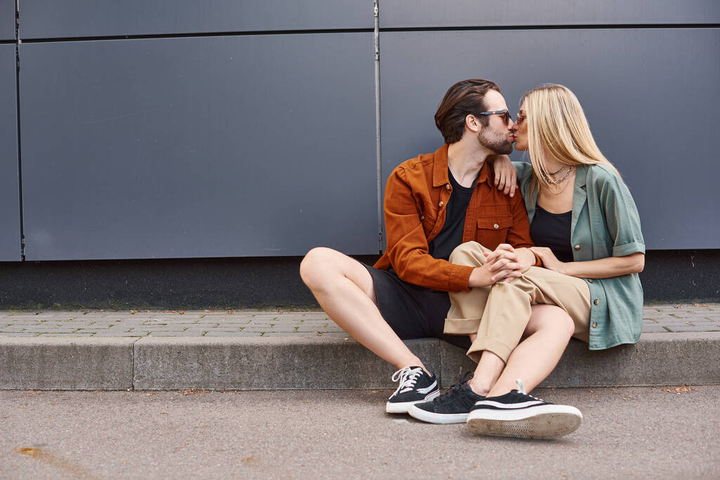 A romantic scene of a sexy couple sitting on the ground, sharing a passionate kiss. - Photo, Image