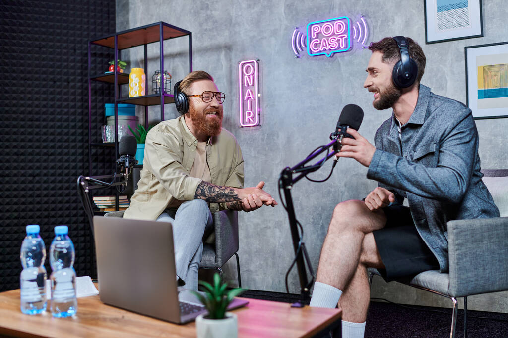 γενειοφόρος όμορφος συνέντευξη και ο επισκέπτης του με ακουστικά στο στούντιο συζητώντας ερωτήσεις, podcast - Φωτογραφία, εικόνα
