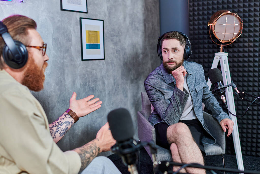 pohledný reportér s rezavými vlasy a jeho host se sluchátky diskutovat otázky, podcast - Fotografie, Obrázek