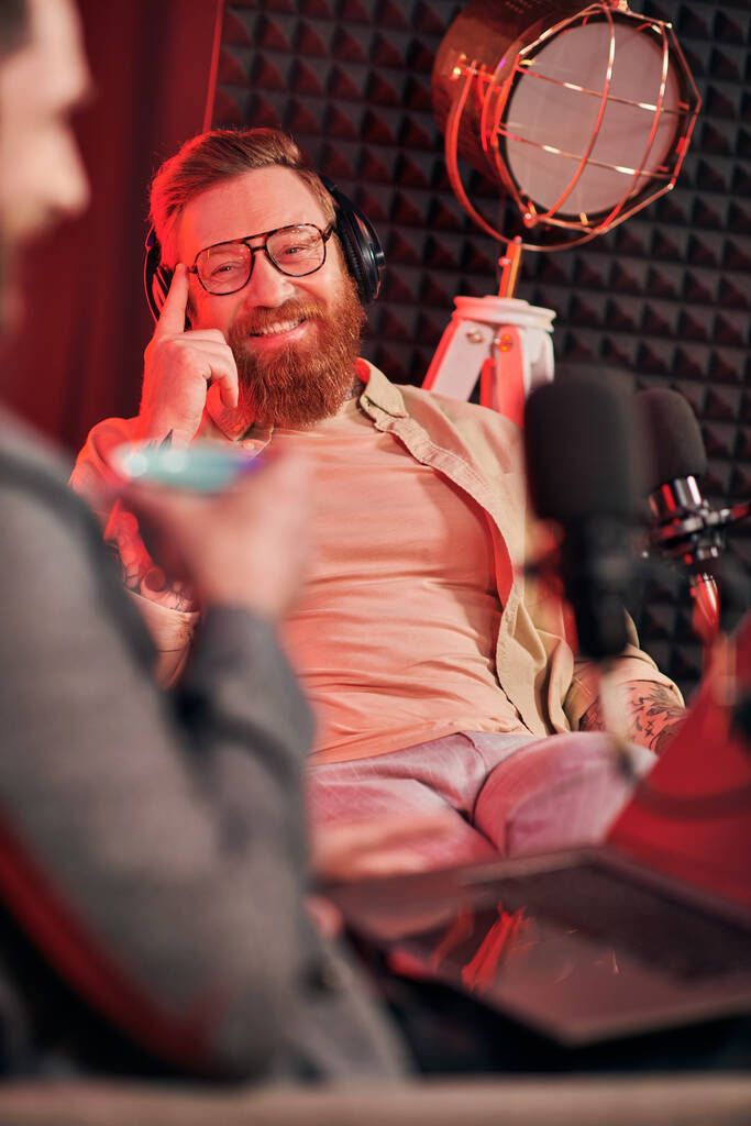 oddaní muži v pohodlných šatech s kávou a sluchátky během diskuse na podcastu - Fotografie, Obrázek