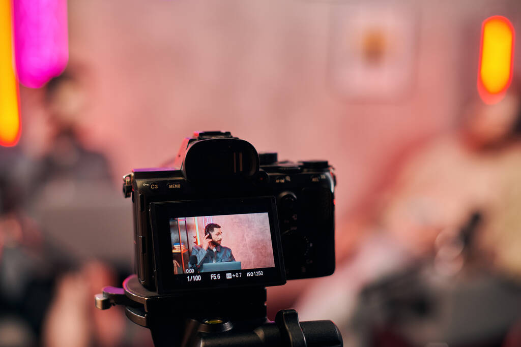 фокус на зйомках фотоапарата бородатий розмитий чоловік з навушниками обговорює питання на подкасті - Фото, зображення