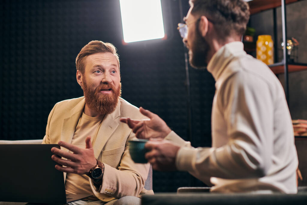 zwei gut aussehende Männer in eleganter Kleidung mit Kaffee und Laptop diskutieren Interviewfragen - Foto, Bild