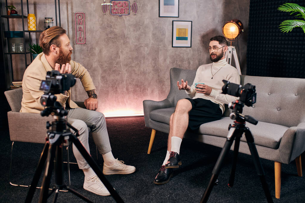 όμορφοι κομψοί άνδρες με κομψά ρούχα της μόδας μιλώντας ενεργά κατά τη διάρκεια της συνέντευξης στο στούντιο - Φωτογραφία, εικόνα