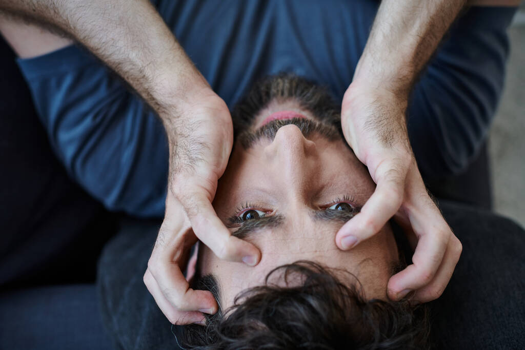 στρεσαρισμένος απελπισμένος άντρας με μούσι σε περιστασιακή ενδυμασία ξαπλωμένος με τα χέρια στο πρόσωπο κατά την ψυχική κατάρρευση - Φωτογραφία, εικόνα