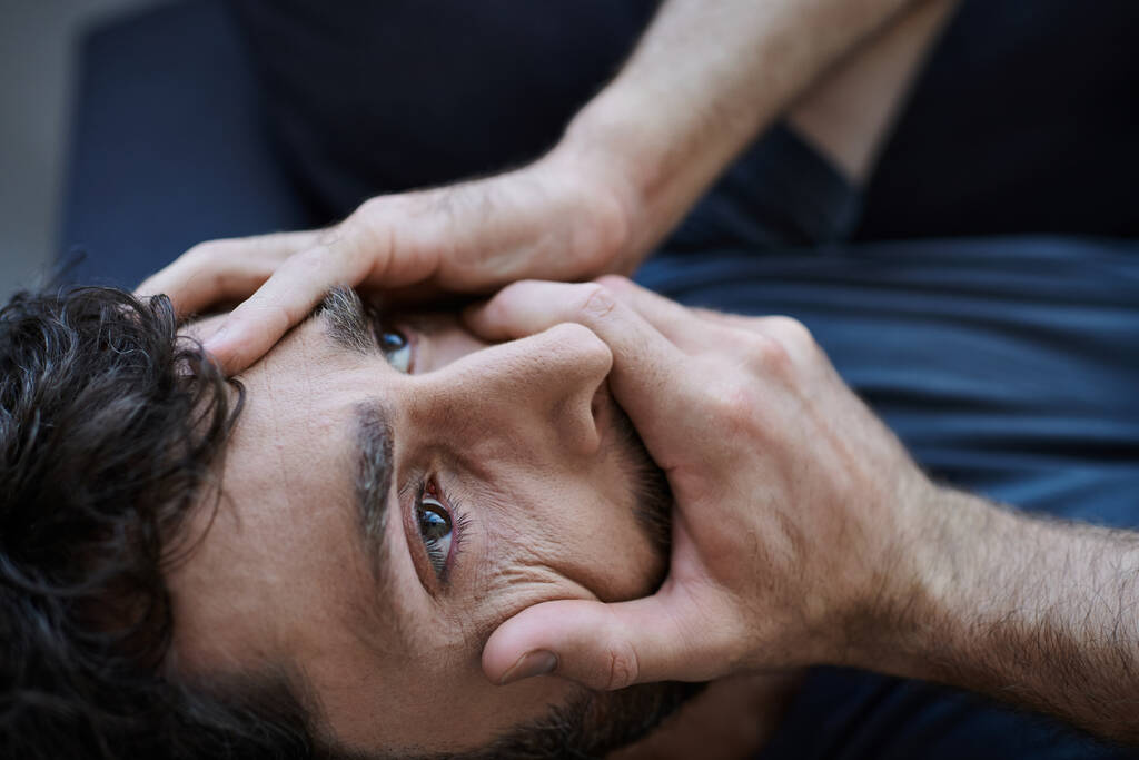 стресовий відчайдушний чоловік з бородою в повсякденному вбранні лежить руками на обличчі під час психічного розладу - Фото, зображення
