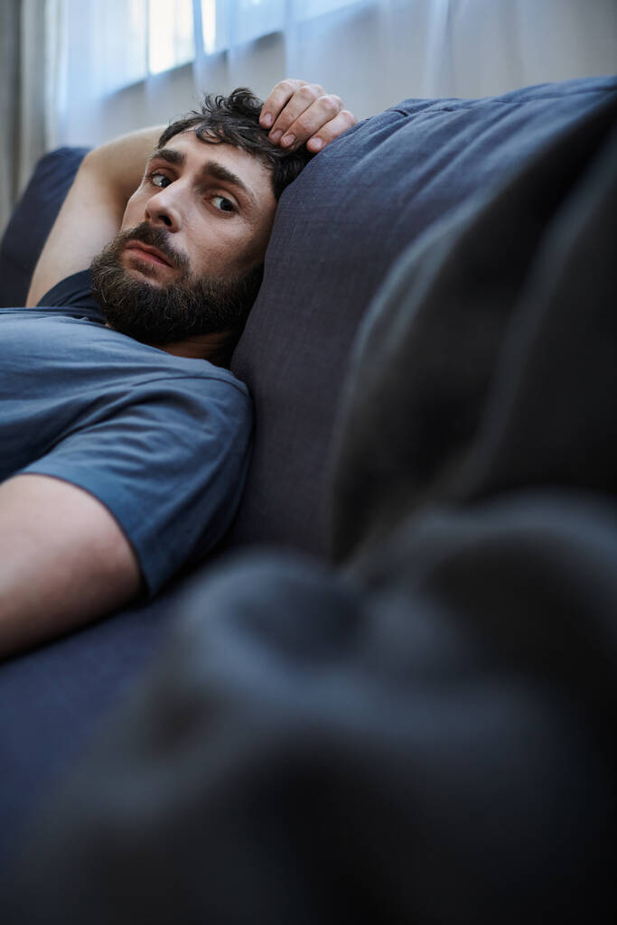 deprimido hombre desesperado en acogedora ropa de casa acostado en el sofá durante la crisis mental, psicoterapia - Foto, imagen