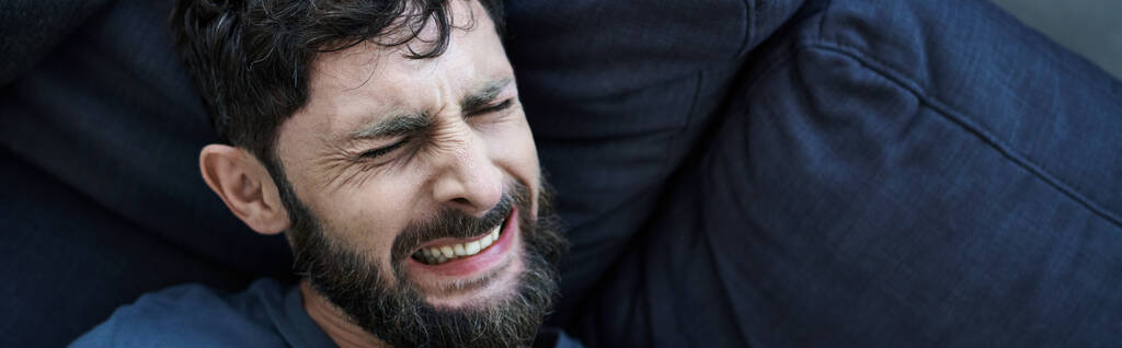 Besorgter Mann mit Bart in Freizeitkleidung, der unter Zusammenbruch leidet, psychisches Gesundheitsbewusstsein, Transparent - Foto, Bild