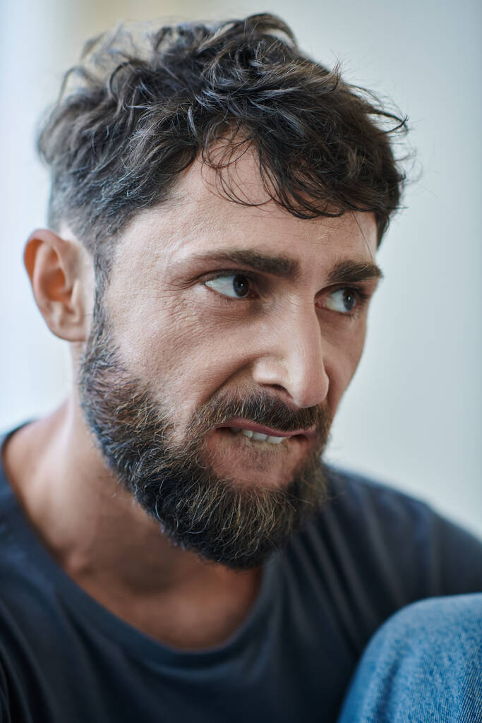 slecht getraumatiseerde man met baard bijten zijn lippen tijdens depressieve episode, geestelijke gezondheid bewustzijn - Foto, afbeelding